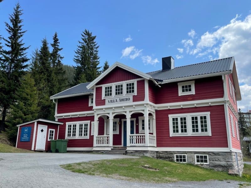 Large older red wooden house with white knots.