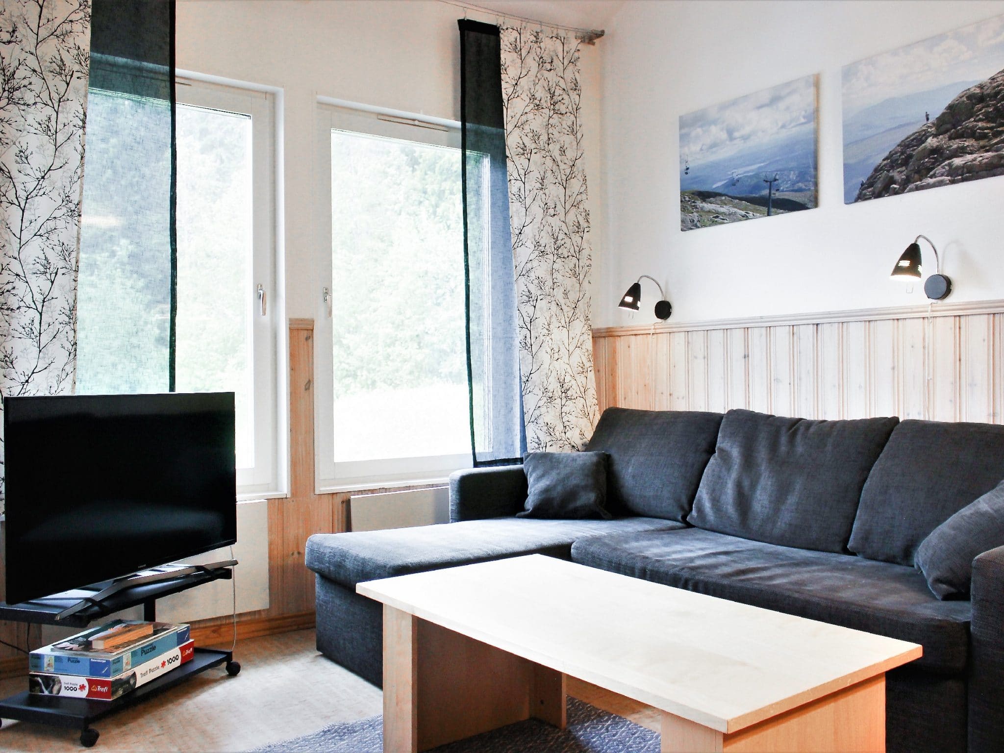 Vardagsrum med TV och soffa i grått tyg